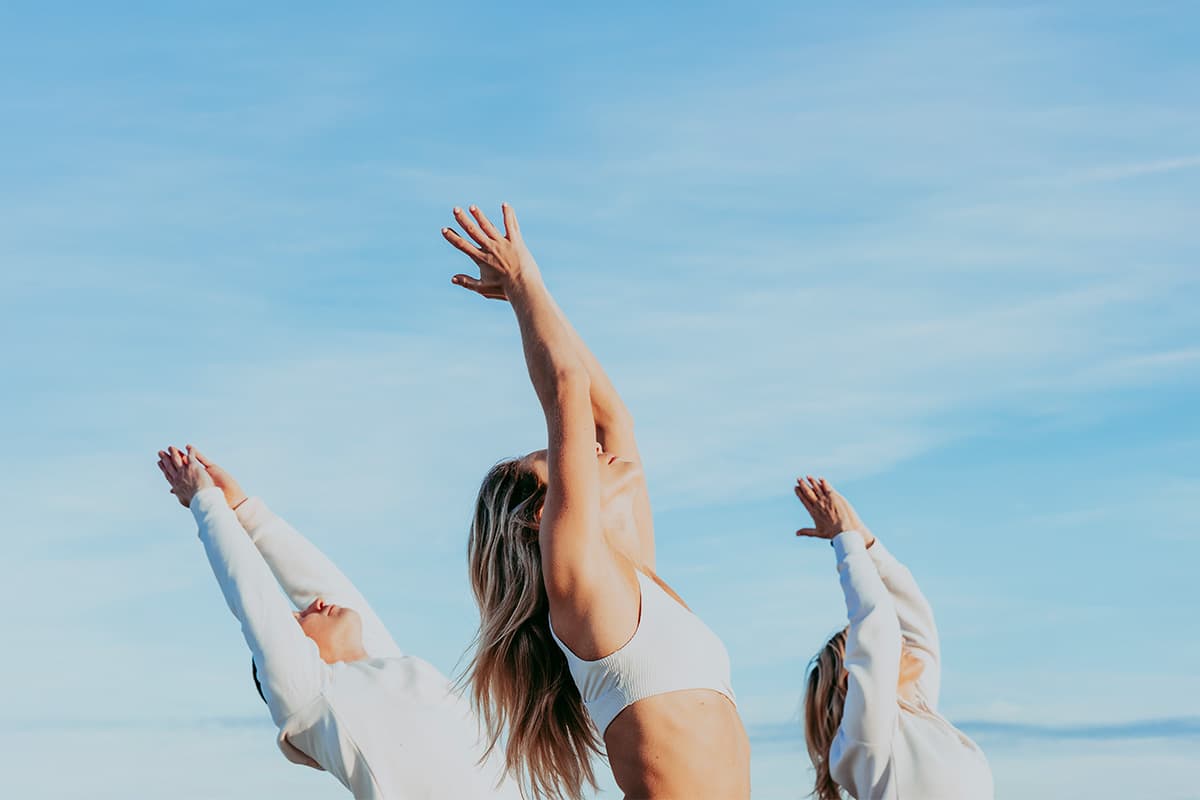 Group of people performing outdoor yoga under a clear blue sky